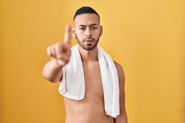 Poster - Young hispanic man standing shirtless with towel pointing with finger up and angry expression, showing no gesture