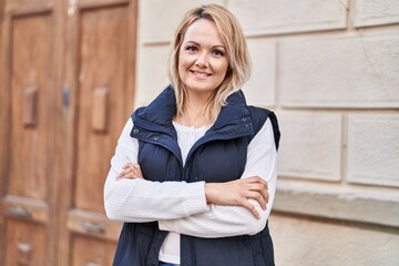 Canvas Print - Young blonde woman standing with arms crossed gesture at street