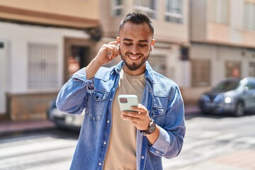 Wall Mural - Young hispanic man smiling confident listening to music at street