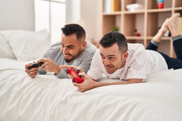 Wall Mural - Two men couple playing video game lying on bed at bedroom