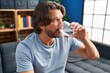 © Krakenimages.com - Middle age man drinking glass of water sitting on sofa at home