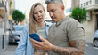 © Krakenimages.com - Man and woman couple using smartphone with serious face at street