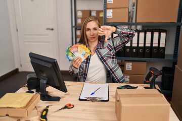 Poster - Young blonde doctor woman working at small business ecommerce holding swiss francs with angry face, negative sign showing dislike with thumbs down, rejection concept