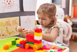 © Krakenimages.com - Adorable blonde girl playing with construction blocks sitting on table at kindergarten