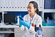 Young Hispanic Woman Scientist Using Smartphone Working At Laboratory