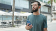 © Krakenimages.com - Young hispanic man using smartphone and earphones at street