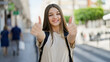 © Krakenimages.com - Young beautiful girl student wearing backpack doing thumbs up gesture at street