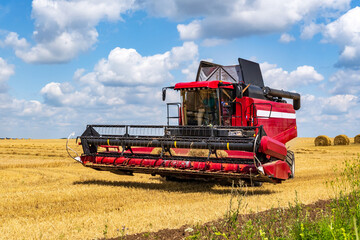 Wall Mural - modern heavy harvesters remove the ripe wheat bread in field. Seasonal agricultural work