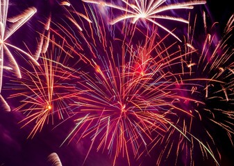 Wall Mural - Abstract background - bright beams of festive colorful fireworks against black night sky.