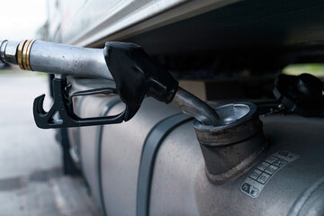 A close-up of a gas station gun inserted into the fuel tank.