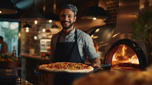 Man Stands In The Kitchen Against A Backdrop Of Pizza And An Oven.