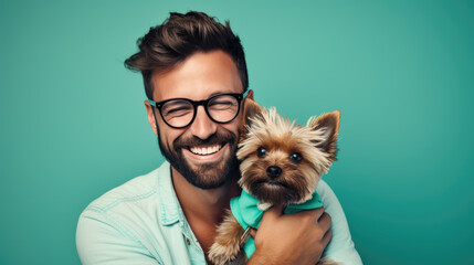 Canvas Print - young man holds a dog puppy in his arms on blue background.