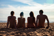 Rear View Of Silhouettes Naked For People Men And Women Sitting On Nudist Sandy Sea Beach. From Behind Of Nude Naturist Friends People, Freedom. Nudism Naturism Lifestyle Concept. Copy Ad Text Space