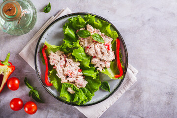 Wall Mural - Canned tuna salad with vegetables on lettuce leaves on a plate top view