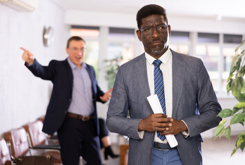 Wall Mural - Upset adult man in business suit and glasses stands with documents in reception..