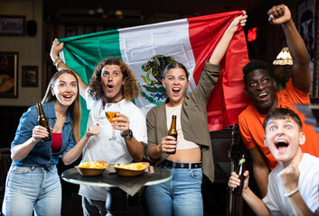 Wall Mural - Joyful fans of the Mexican team celebrating the victory in the night bar