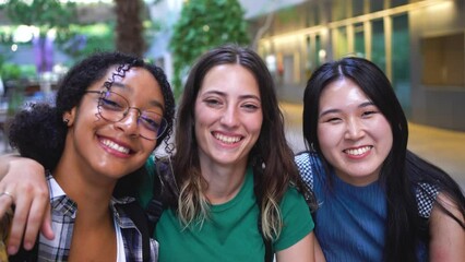 Wall Mural - Three college student girls taking a selfie at the university campus during a class break.