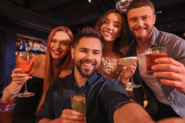 Canvas Print - Happy friends with cocktails taking selfie together in bar