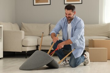 Poster - Man with screwdriver assembling armchair on floor at home