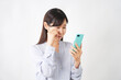 © siro46 - スマートフォンで電話するスマートフォンを持って泣くミドルエイジの女性　白背景