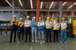 © chadchai - Industrial teamwork. Professionals donning safety hard hats standing together in a bustling factory.