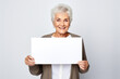 Happy mature senior woman holding blank white banner sign, isolated studio portrait.