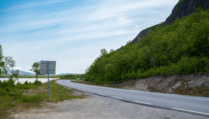 Wall Mural - Asphalt road on the coast with small trees and hills