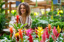 Smiling Woman Choosing Colorful Flowers At Nursery