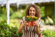 Happy Woman Holding Red And Yellow Pepper Plants In Nursery