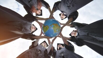 Wall Mural - Graduating students hug and toss a geographical globe of the world overlooking north and south america.