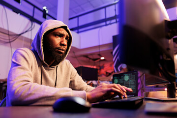 Poster - Concerned hacker cracking password and breaching into computer network system. Concentrated african american man in hood engaging in online criminal activity and breaking law