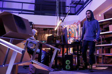 Poster - Hacker leaving abandoned warehouse after hacking network system. Asian criminal standing in hideout place after doing crime activity and breaking into online server at night