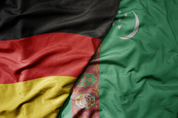 big waving realistic national colorful flag of germany and national flag of turkmenistan .