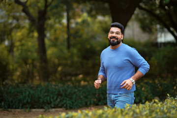 Wall Mural - Young indian man running or jogging at park.