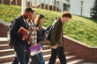 © standret - Walking, holding notepads. Four young students in casual clothes are together outdoors