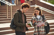 With educational materials, notepad. Man and woman students are together outdoors near university