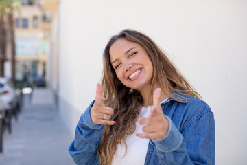 Wall Mural - pretty hispanic woman feeling happy, cool, satisfied, relaxed and successful, pointing at camera, choosing you