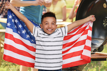 4th of July - Independence day of America. Family having picnic in park. Happy little boy with national flag of United States