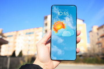 Wall Mural - man using weather forecast app on smartphone outdoors on sunny day, closeup. data and illustration o