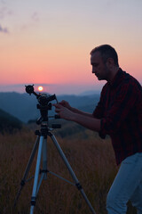 Wall Mural - astronomer looking at the sun with a telescope and using a cellphone.