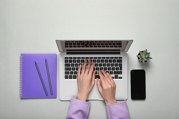 Wall Mural - Woman using laptop at light table, top view