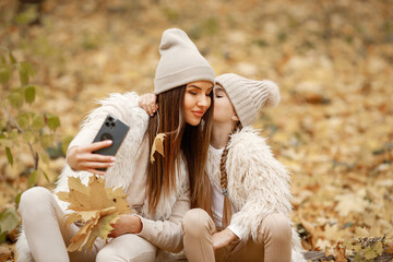 Mother and her daughter make a selfie in autumn forest