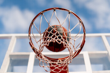 A close-up of a basketball hoop into which a basketball hits the concept of admiration for the game of basketball and love of working out 