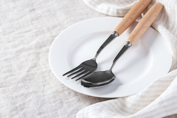 Wall Mural - White plate with fork, spoon and linen napkin on table