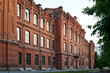 Perspective of long red brick building or historical monument consisting of three storeys standing in the street of modern city