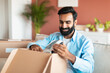 © Prostock-studio - Indian buyer man unpacking box with new device at home