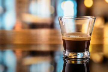 Wall Mural - Glass of steaming hot espresso coffee on the bar counter with bokeh background.