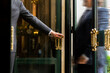 © Damien Guillaume - Luxury service gesture – Business man holding a door handle with blurred motion of a guest entering a high-end establishment
