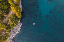 Aerial View Of A Sailing Boat Moored Along The Cliffs In The Mediterranean Sea At Sunset, Maratea, Potenza, Italy.