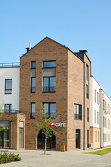 Wall Mural - Corner of large three storey block of flats with small cafe on front part standing in the central street of town or rural environment